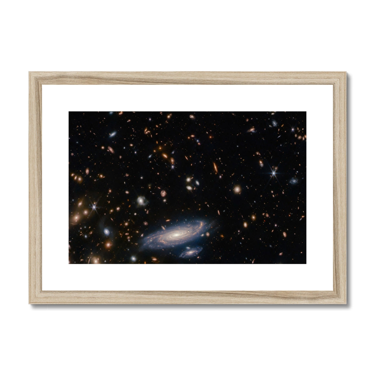 Spiral Amongst Thousands framed and mounted print showing a spiral galaxy among distant galaxies in a natural wood frame, front view
